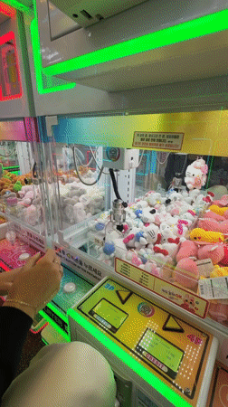 Person plays claw machine at neon-lit Seoul arcade