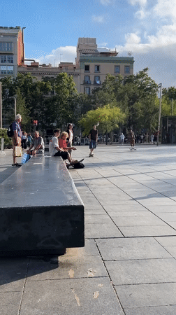 Skateboarders perform tricks in Barcelona public plaza