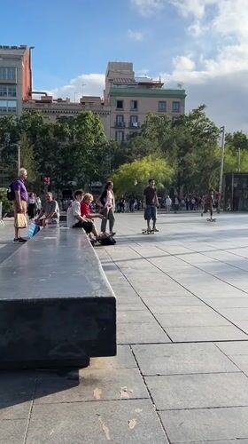 Skateboarders perform tricks in Barcelona public plaza