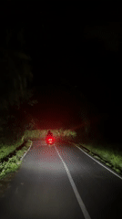 Motorcycle travels narrow road at night in Ubud