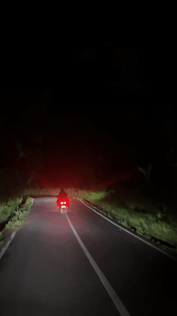 Motorcycle travels narrow road at night in Ubud