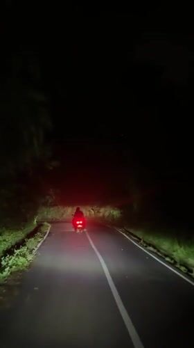 Motorcycle travels narrow road at night in Ubud