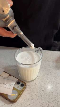 Person prepares whipped cream drink amid daisies in Novi Sad