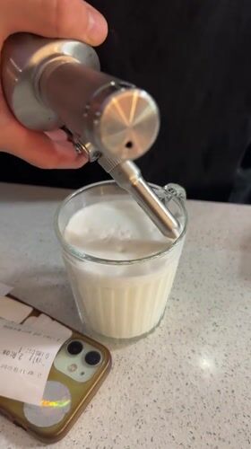 Person prepares whipped cream drink amid daisies in Novi Sad