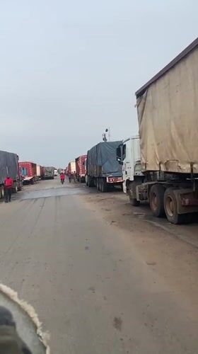 Semi-trucks line street in Karmajiji, Nigeria during morning hours