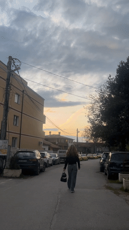 Woman walks residential street during Sofia dusk hours