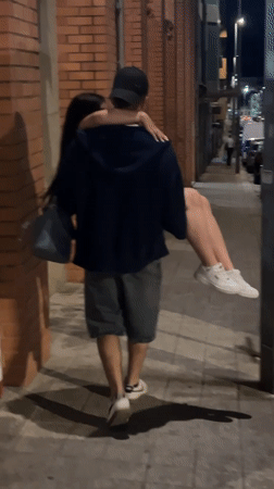Man carries woman on Porto sidewalk at night