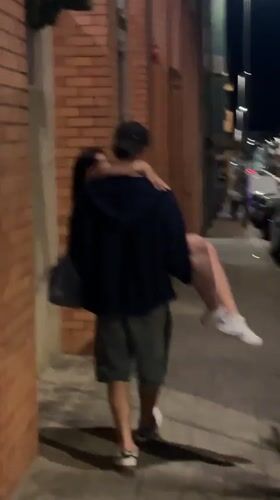 Man carries woman on Porto sidewalk at night