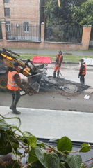 Road crew conducts manhole repair work with heavy equipment