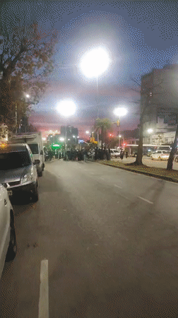 Street crowd blocks traffic in Wilde, Argentina at dusk