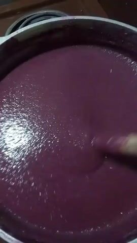 This media file captures a close-up view of a pot filled with a thick, dark purple liquid, likely a purée or a smoothie, being stirred. A utensil, possibly a spoon or spatula, is visible as it moves through the mixture, creating ripples and highlights on the surface. The lighting suggests an indoor setting, possibly a kitchen, with a bright reflection on the liquid indicating a light source above or to the side. The color of the liquid is a deep, rich purple, with hints of a reddish hue. The texture appears smooth and consistent, with small air bubbles or undissolved particles visible in certain areas. The overall impression is of a culinary preparation in progress. No people are visible in the frame, and there is no discernible text. The time of day and weather are not apparent from the imagery. The provided location context "Aatsy, Abkhazia" does not offer any visual cues within the media file itself.