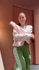 Young woman dances in hallway wearing pink sweatshirt