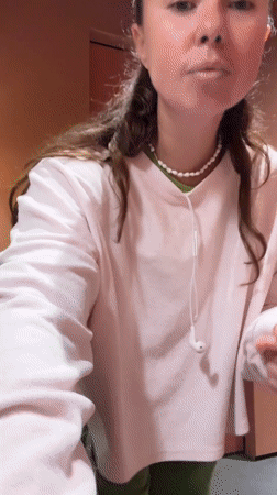 Young woman dances in hallway wearing pink sweatshirt