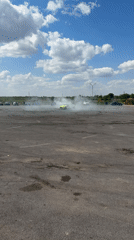 Cars and a motorcycle run practice drills in an empty lot