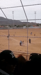 Baseball game observed from stands behind chain-link fence
