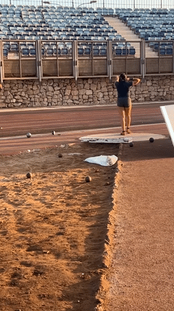 Shot put athletes train at dusk in an Arica stadium