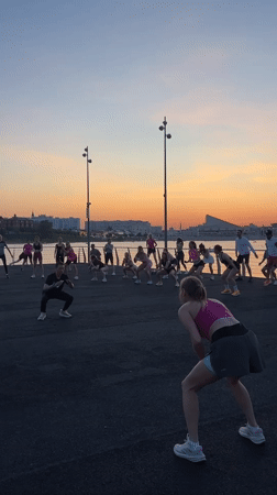 Evening fitness class conducts outdoor workout near water in Kazan