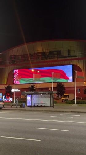 Minsk at night: flags, lit architecture, and a Belarusian cultural poster