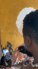 Artist observed painting on large canvas while wearing distinctive jewelry