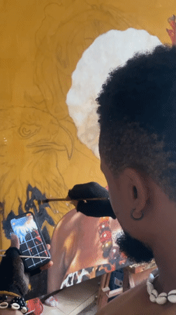 Artist observed painting on large canvas while wearing distinctive jewelry