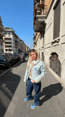 Woman in denim jacket walks sunny Milan sidewalk
