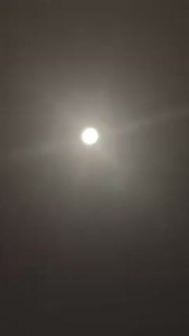 A bright, round light source shines against a dark background.