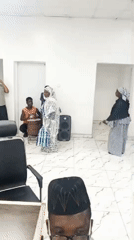 Indoor gathering observed in white-walled room during midday
