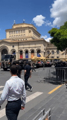 Military parade displays drones on trucks under sunny skies