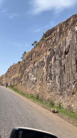 Rocky cliff face documented along paved road in Nigeria