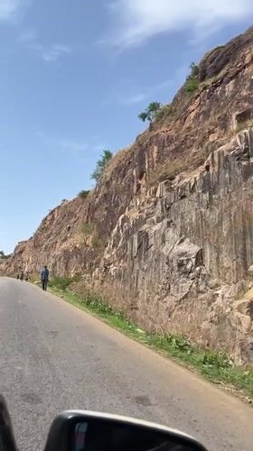 Rocky cliff face documented along paved road in Nigeria