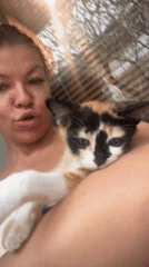 Woman holds calm calico kitten indoors in North Kuta