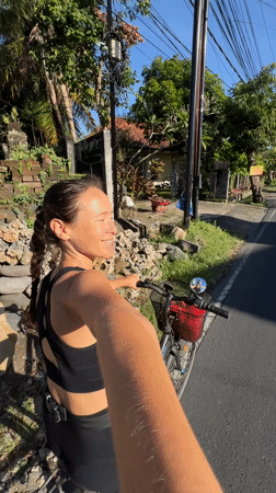 Woman with bicycle stops on roadside in Singakerta, Indonesia