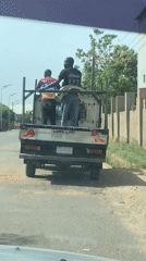 Two men ride in pickup truck bed in Jos