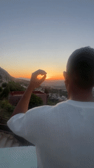 Person watches sunset from elevated viewpoint over Tétouan, Morocco