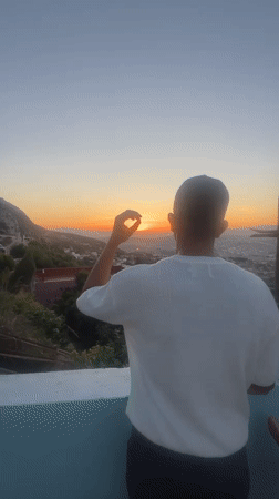 Person watches sunset from elevated viewpoint over Tétouan, Morocco