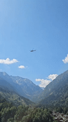 Helicopter with sling load over Italian alpine valley
