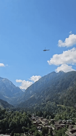 Helicopter with sling load over Italian alpine valley