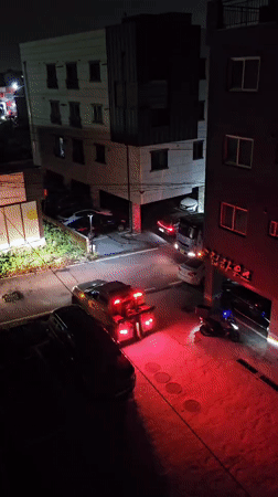 Tow truck with hazard lights parked outside Asan-si building at night