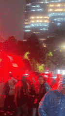 Rainy night crowd with flares and Mexican flag in city street
