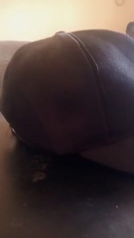 A close-up video shows a black Nike baseball cap resting on a dark surface. The camera focuses on the cap, revealing a white Nike swoosh logo on the side. The background is blurred.