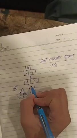 A close-up shot shows a person's right hand holding a blue pen, drawing on a ruled notebook page. The notebook page is partially visible, and a patterned fabric, possibly a blanket or carpet, is visible in the upper left corner. On the notebook page, a hopscotch grid has been drawn with numbers from 1 to 8. Below the hopscotch grid, a simple drawing of a person with a smiley face is visible. The pen is currently positioned over the numbers 2 and 1 in the hopscotch grid. To the right of the hopscotch grid, the phrase "that never grow old" is written.