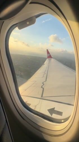 Aircraft flies over populated Kuta area in golden sunlight