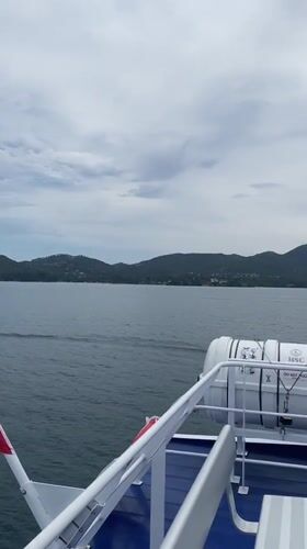 Ferry with Thai flag cruises waters near Baan Sri Thanu