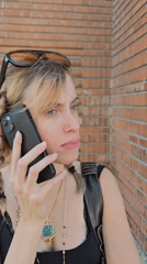 Woman makes phone call near brick wall in Massy