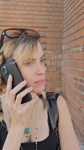 Woman makes phone call near brick wall in Massy
