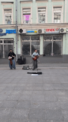 Street musicians perform guitar and drums on Moscow sidewalk
