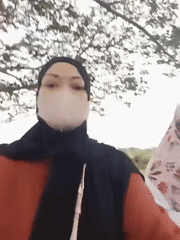 Two women in hijabs walk on paved path