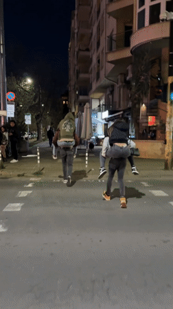Friends share piggyback rides on Sofia street at night