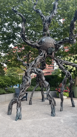 Dark metal kinetic sculpture with sphere on display in Cambridge