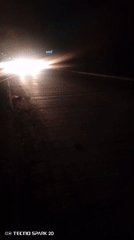 Nighttime traffic observed near illuminated gas station